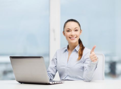 business and technology concept - businesswoman with laptop in office showing thumbs up