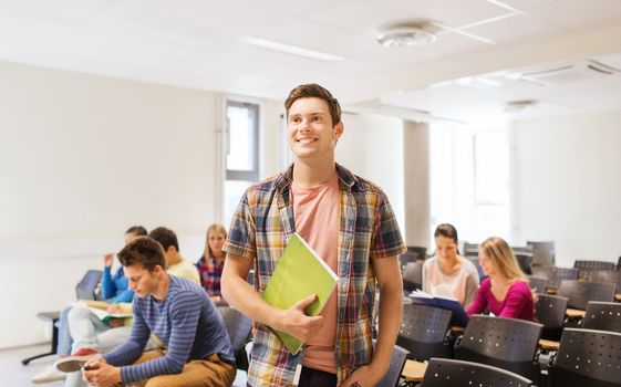 education, high school, teamwork and people concept - group of smiling students with notepads sitting in lecture hall