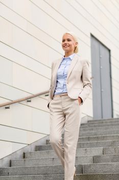 business, people and education concept - young smiling businesswoman walking down stairs outdoors