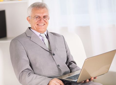 Happy Senior businessman working on laptop.