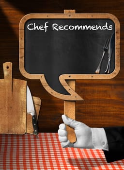 Hand of chef with white glove holding a pole with empty blackboard in the shape of speech bubble with text Chef Recommends