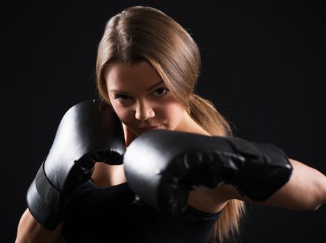 Portrait of Young beautiful boxing girl is giving a croshe punch.