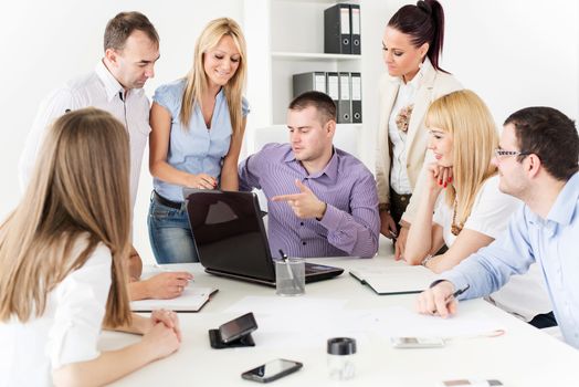 Happy Business people in the office discussing project on laptop at meeting.