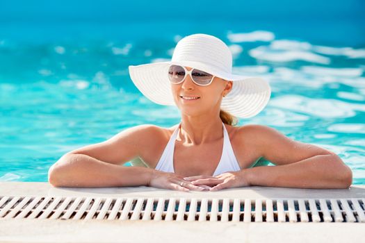 Young beautiful woman enjoying the sun in the pool.