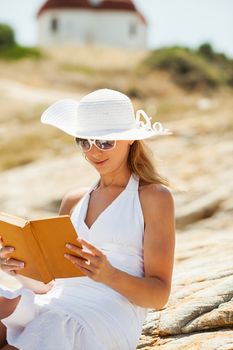 Beautiful Girl with a book sitting on the rock and Expressing Positivity.