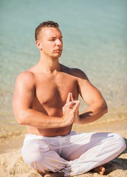 Young man meditating on the beach.