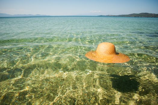 Straw sun hat float in the transparent seawater.