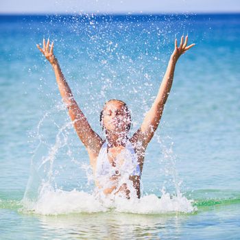 Beautiful happy woman splashing in the sea