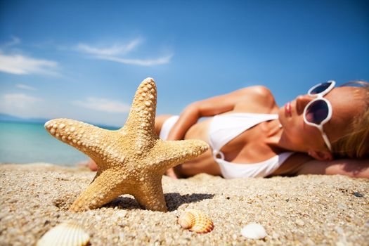 Starfish and beautiful young woman on the beach. Selective focus. Focus on the starfish.