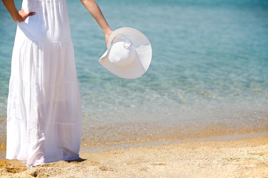 woman holding a white hat at the beach