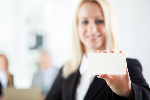 Beautiful young businesswoman holding Blank business card in the office. Looking at camera. Selective Focus.