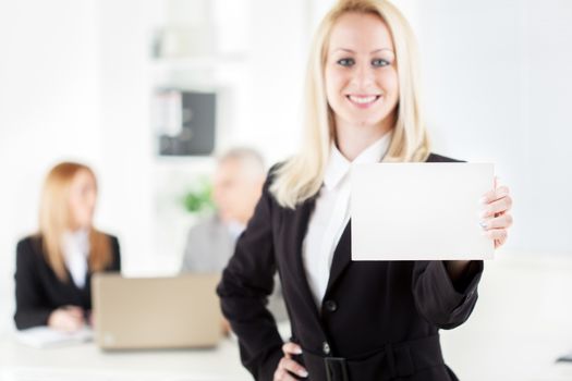 Beautiful young businesswoman holding Blank business card in the office. Looking at camera. Selective Focus.