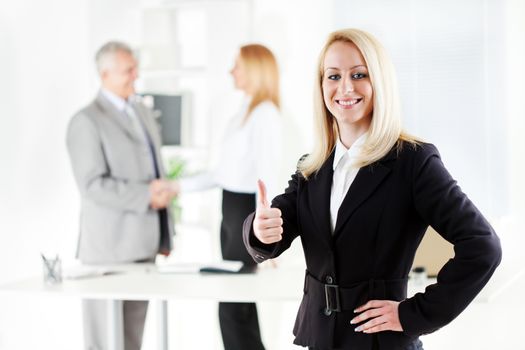 Happy Beautiful young businesswoman showing thumbs up in the office. Looking at camera. Selective Focus.