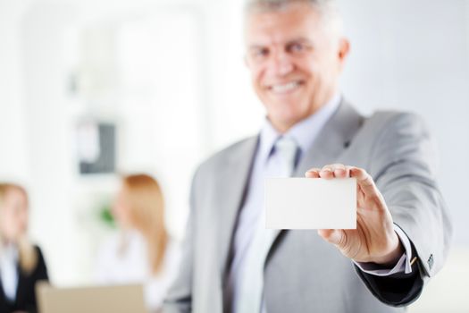 Happy senior businessman holding Blank business card in the office. Looking at camera. Selective Focus.