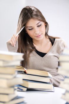 Beautiful Student girl learning and thinking between many books. Selective focus.