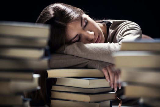 Tired student fell a sleep between many books, while learning. Selective focus.