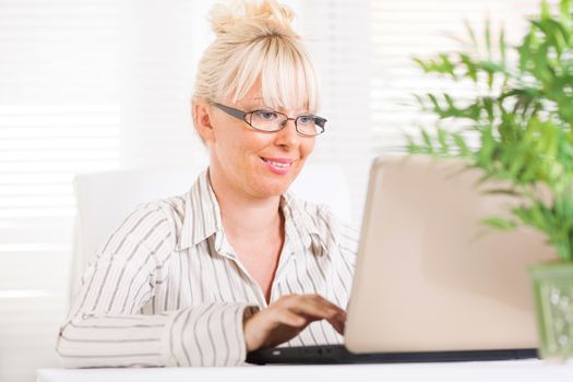 Beautiful mature Business woman working at laptop in the office