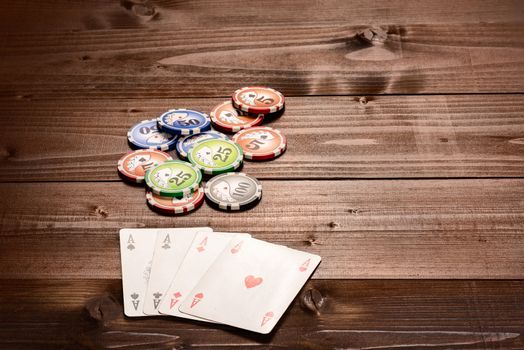 Four aces and chips, vintage poker game playing cards on a wood table