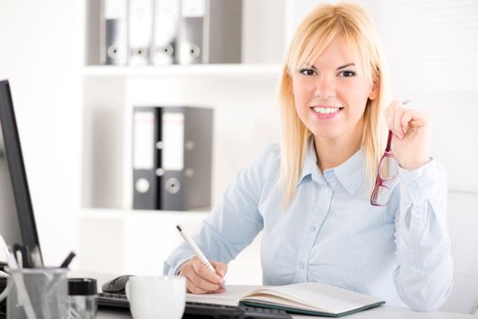 Businesswoman in the office. Sitting at the table and Looking at camera.