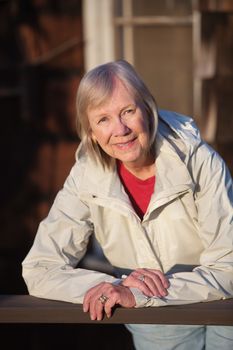 Happy senior adult female leaning on railing outdoors