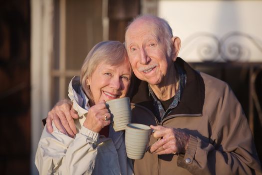 Cheerful white senior couple holding coffee mugs
