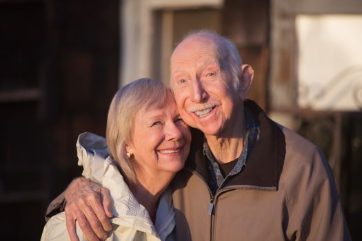 Grinning older couple embracing while standing outdoors