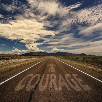 Conceptual image of desert road with the word courage and arrow
