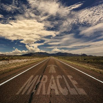 Conceptual image of desert road with the word miracle and arrow