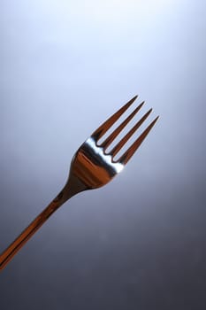 Closeup of new steel fork on dark background