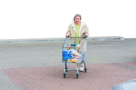Mature woman, pensioner after shopping with full shopping trolley.