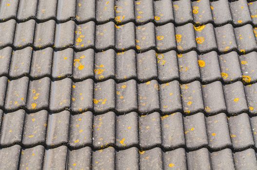 Detail some old house roof with mossy and weathered roof tiles.
