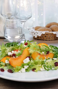 Salad of lettuce and arugula with peaches, feta cheese, cranberries