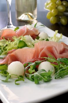 Salad of arugula, lettuce, ham with melon