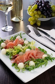 Salad of arugula, lettuce, ham with melon