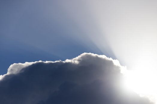 sun rays peering through the edge of a big fluffy cloud