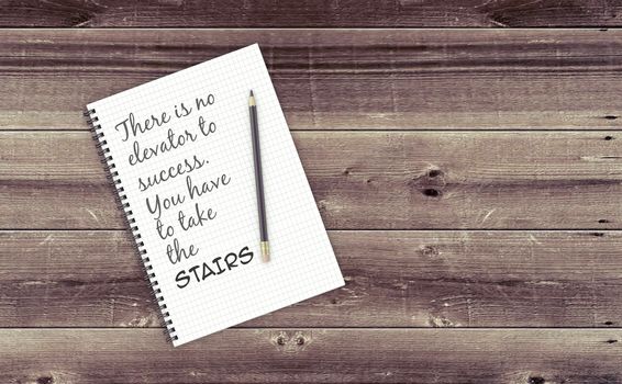 Inspirational quote on notepad.
THERE IS NO ELEVATOR TO SUCCESS. YOU HAVE TO TAKE THE STAIRS.