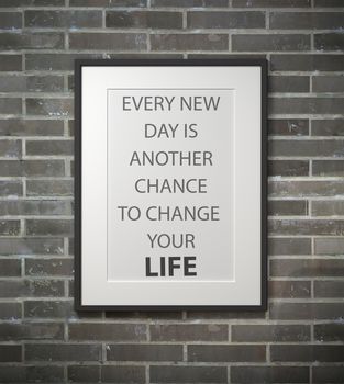 Inspirational quote on picture frame over a dirty brick wall. EVERY NEW DAY IS ANOTHER CHANCE TO CHANGE YOUR LIFE.