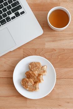 Laptop computer with japanese fished shaped cake and tea