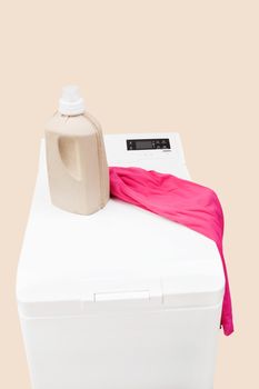 Laundry background. Top loading washing machine with natural organic detergent and colorful clothing isolated. 