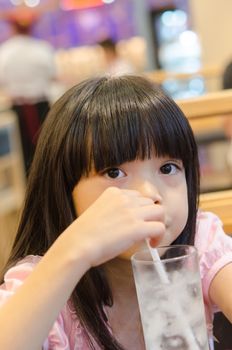little girl drinks water from a glass