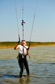 A young woman kite-surfer rides in summer day