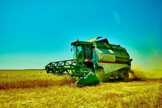 Harvester combine harvesting wheat on sunny summer day.