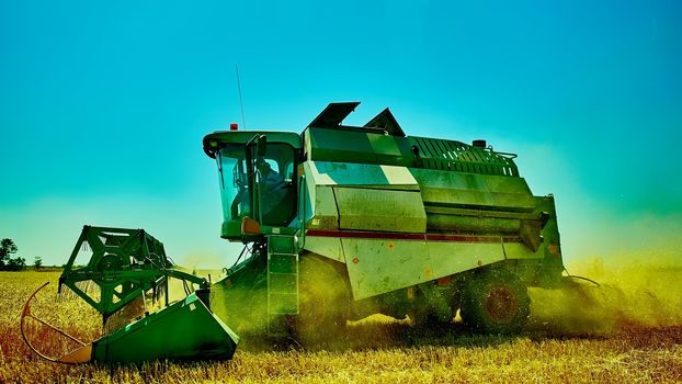 Harvester combine harvesting wheat on sunny summer day.