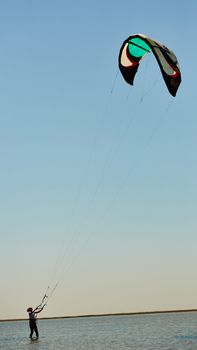 A young woman kite-surfer rides in summer day