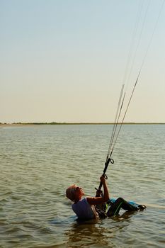 A young woman kite-surfer rides in summer day