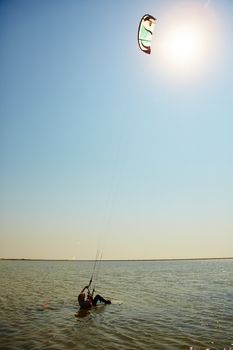 A young woman kite-surfer rides in summer day