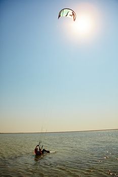 A young woman kite-surfer rides in summer day