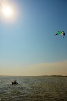 A young woman kite-surfer rides in summer day