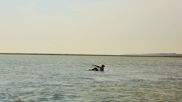 A young woman kite-surfer rides in summer day