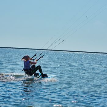 A young woman kite-surfer rides in summer day